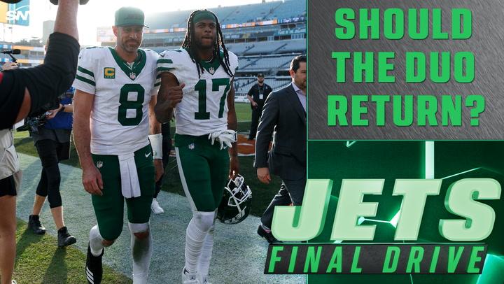 Football players in green uniforms walk off the field; text reads, "Should the duo return?"