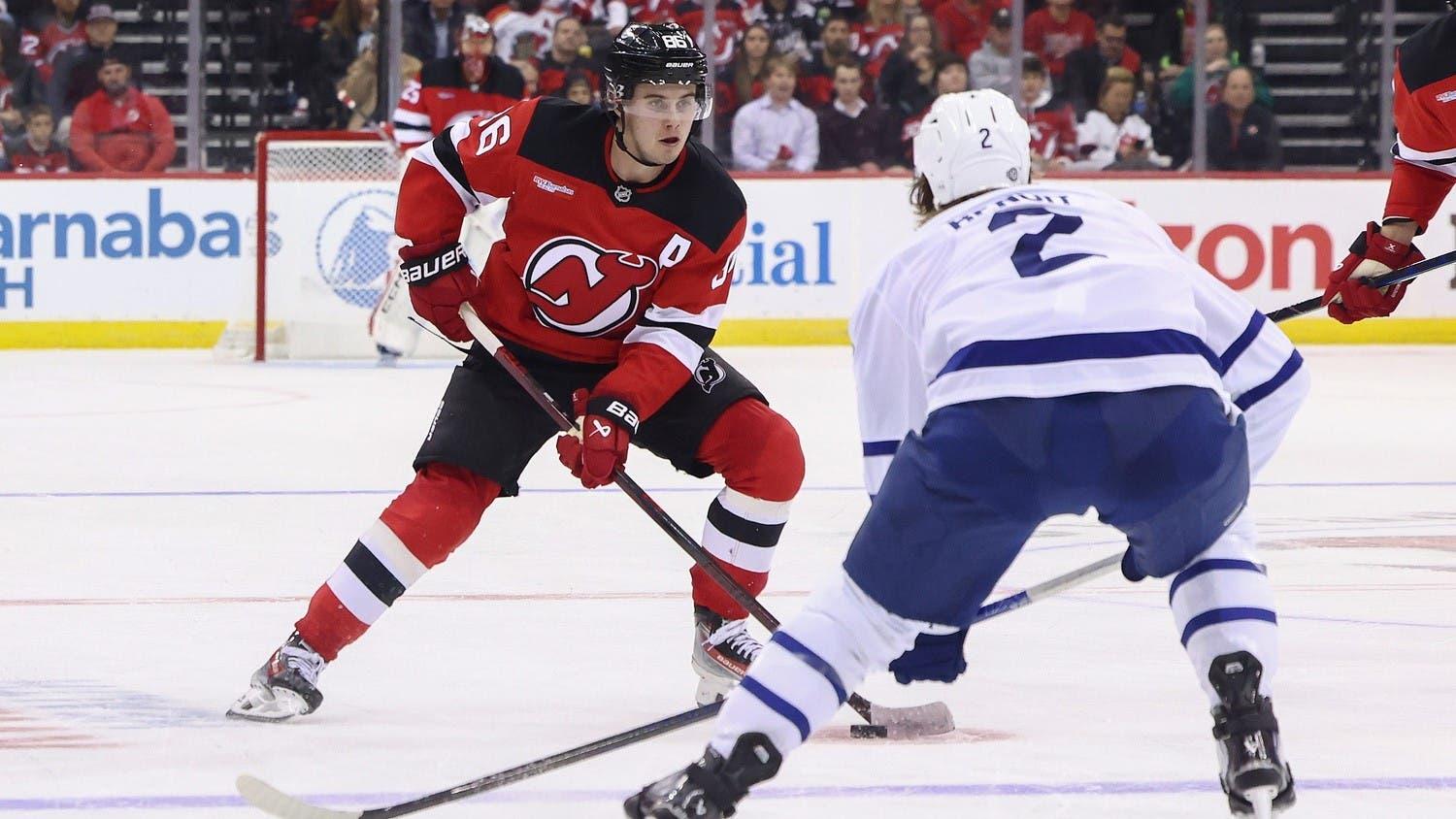 Oct 10, 2024; Newark, New Jersey, USA; New Jersey Devils center Jack Hughes (86) skates with the puck while being defended by Toronto Maple Leafs defenseman Simon Benoit (2) during the second period at Prudential Center. / Ed Mulholland-Imagn Images