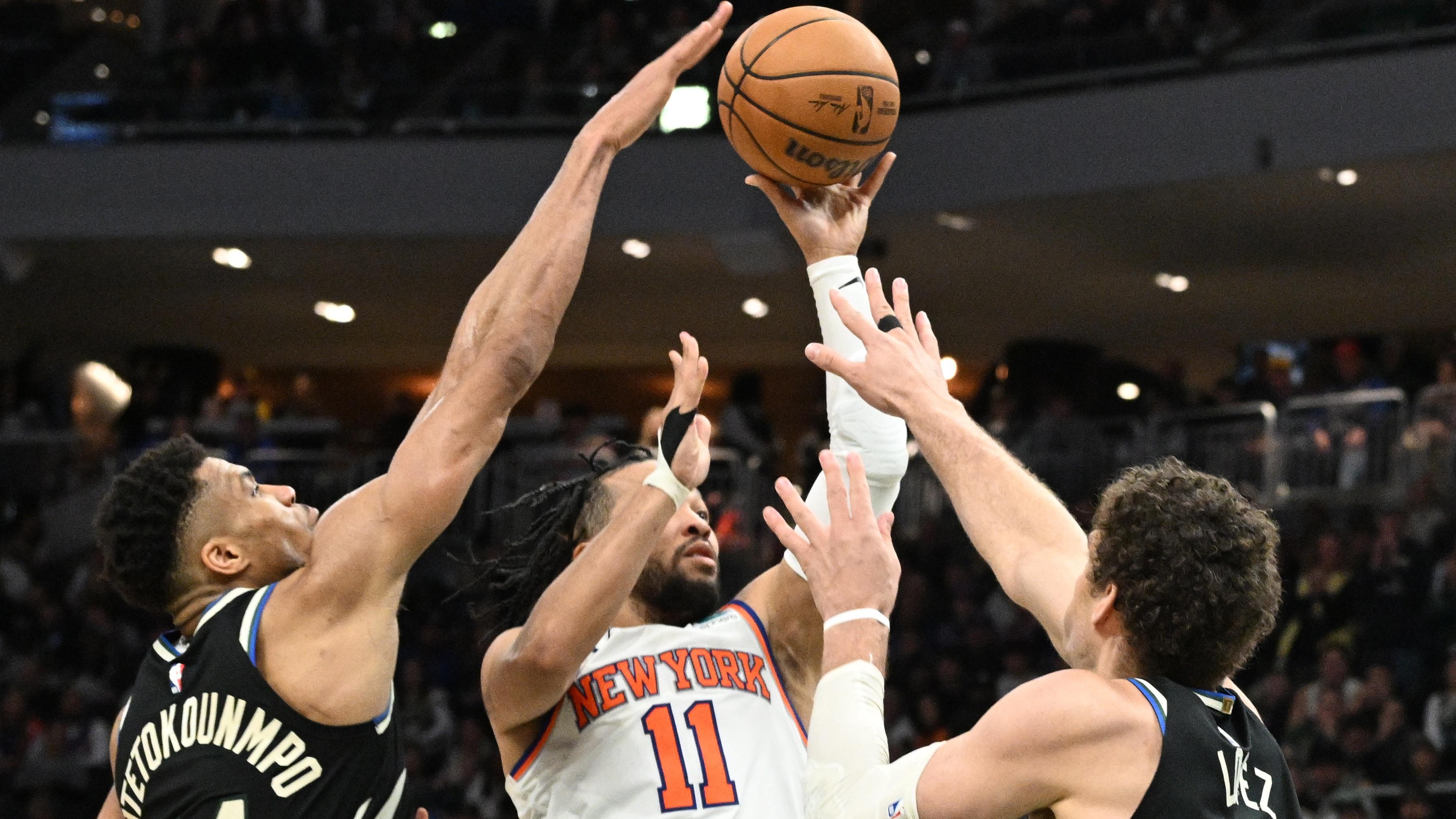 Apr 7, 2024; Milwaukee, Wisconsin, USA; New York Knicks guard Jalen Brunson (11) puts up a shot against Milwaukee Bucks forward Giannis Antetokounmpo (34) and Milwaukee Bucks center Brook Lopez (11) in the second half at Fiserv Forum. Mandatory Credit: Michael McLoone-USA TODAY Sports