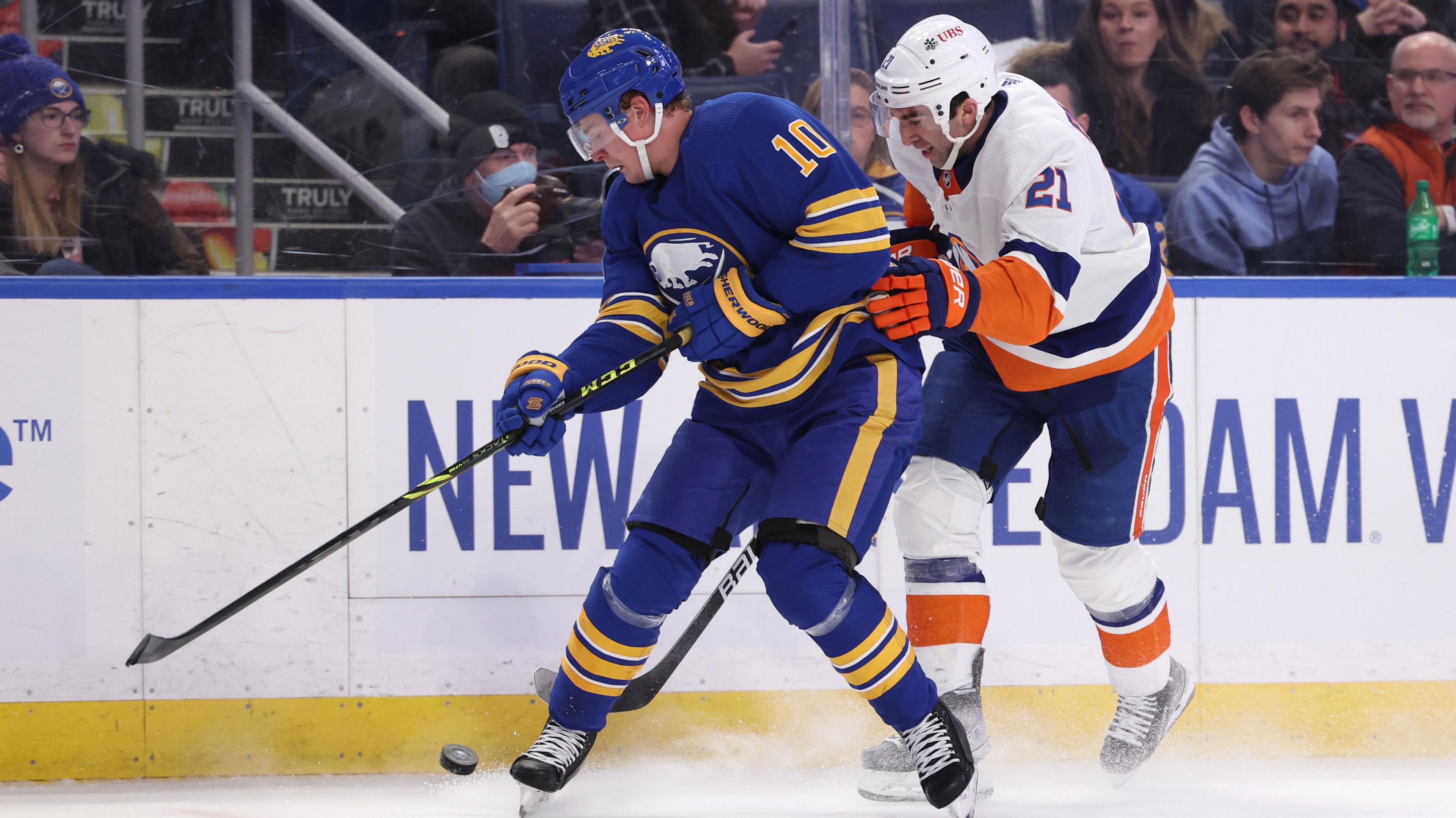 Feb 15, 2022; Buffalo, New York, USA; Buffalo Sabres defenseman Henri Jokiharju (10) and New York Islanders right wing Kyle Palmieri (21) go after a loose puck along the boards during the first period at KeyBank Center.