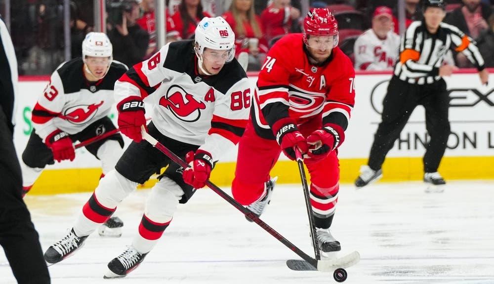 New Jersey Devils center Jack Hughes (86) skates with the puck past Carolina Hurricanes defenseman Jaccob Slavin (74) during the second period at PNC Arena. / James Guillory-Imagn Images