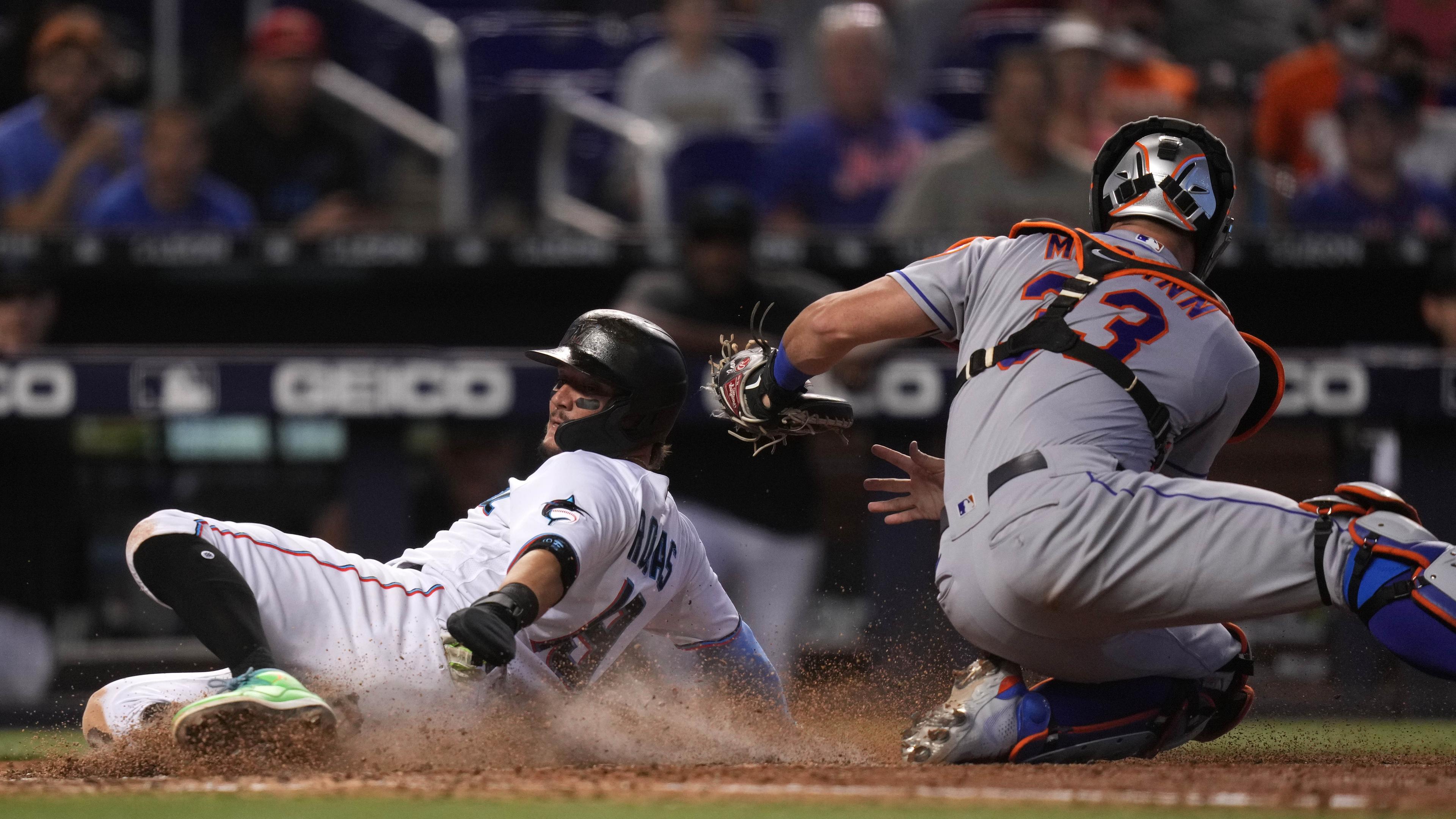 Miami Marlins shortstop Miguel Rojas (19) scores a run past the tag of New York Mets catcher James McCann (33) in the 8th inning at loanDepot park.