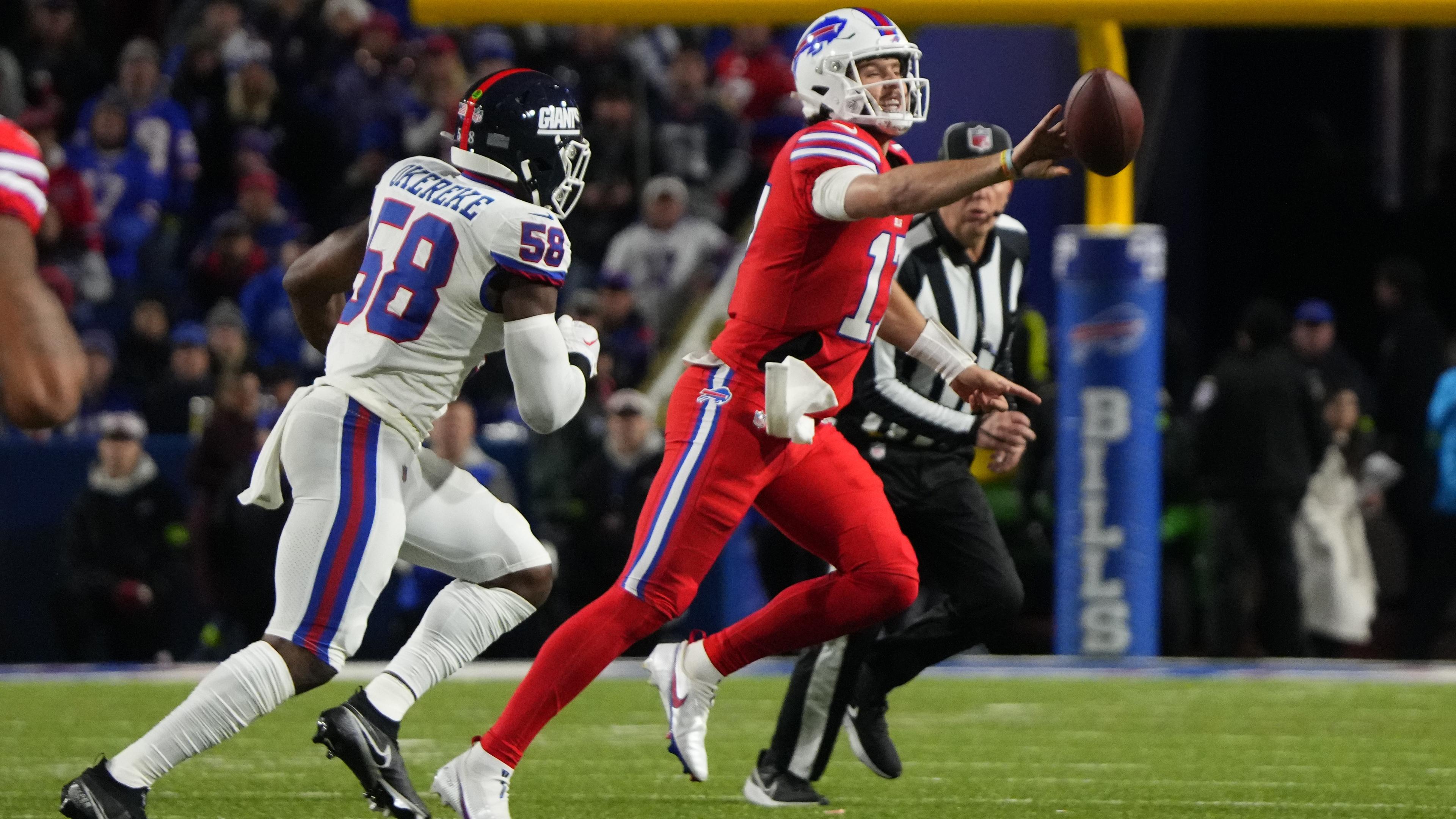 Oct 15, 2023; Orchard Park, New York, USA; Buffalo Bills quarterback Josh Allen (17) flips the ball with New York Giants linebacker Bobby Okereke (58) applying pressure during the first half at Highmark Stadium. Mandatory Credit: Gregory Fisher-USA TODAY Sports