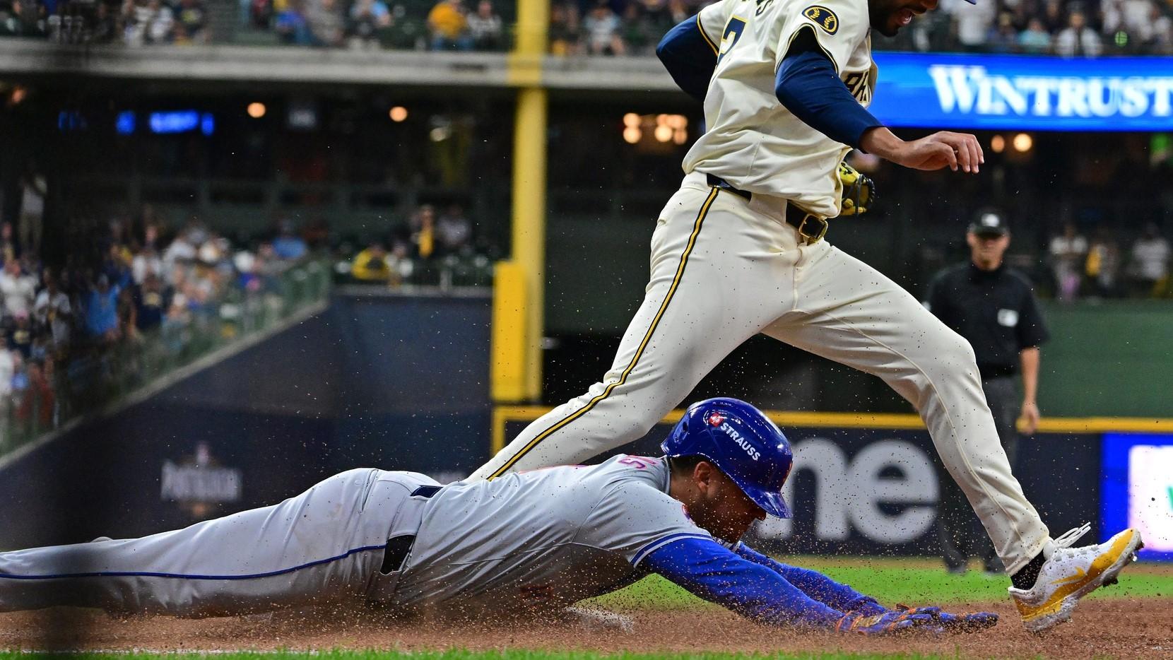 Oct 1, 2024; Milwaukee, Wisconsin, USA; New York Mets second base Jose Iglesias (11) slides safely for a hit against Milwaukee Brewers pitcher Joel Payamps (31) during the fifth inning in game one of the Wildcard round for the 2024 MLB Playoffs at American Family Field.