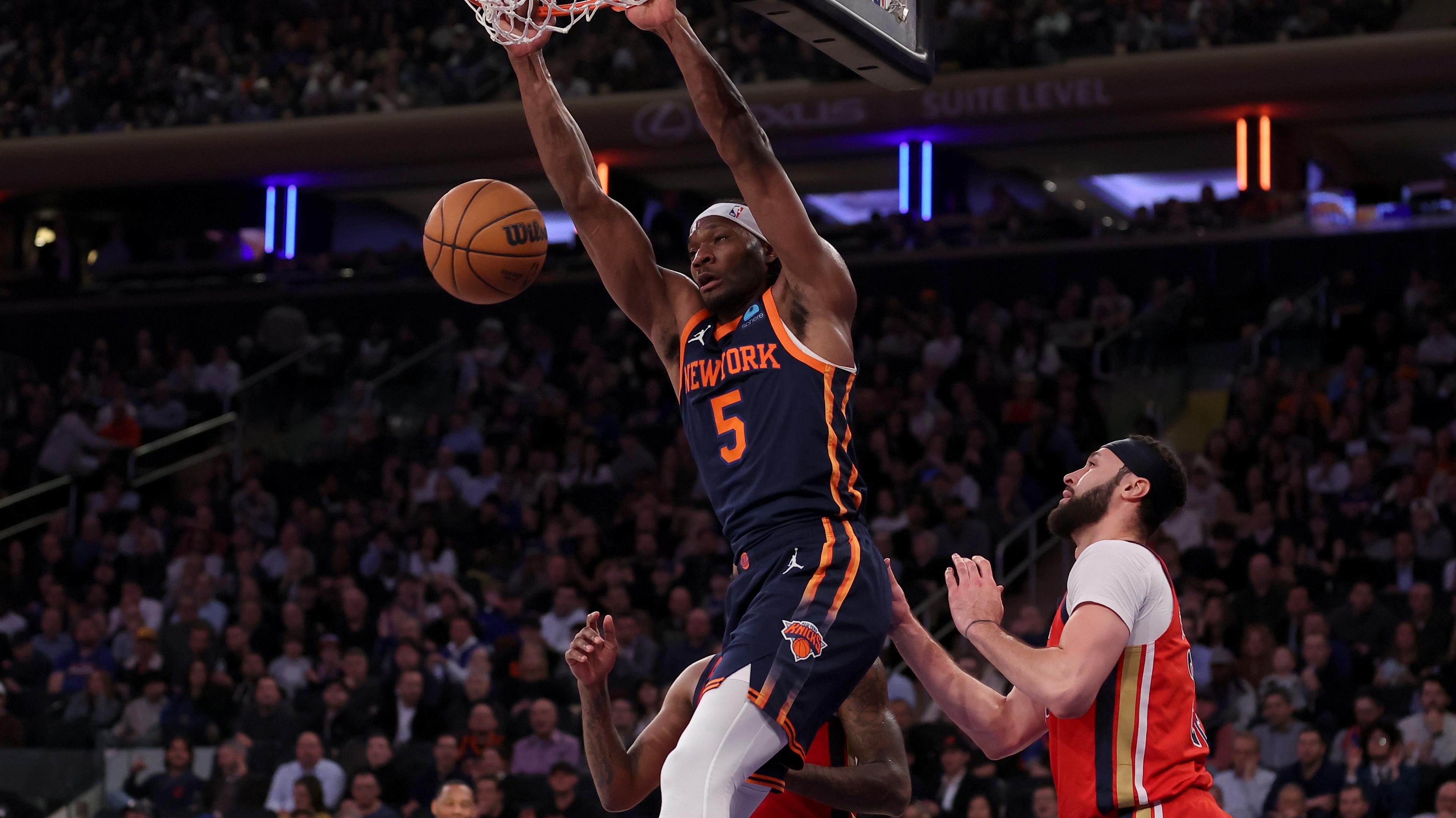 New York Knicks forward Precious Achiuwa (5) hangs on the rim after a dunk against New Orleans Pelicans forwards Naji Marshall (8) and Larry Nance Jr. (22) during the second quarter at Madison Square Garden