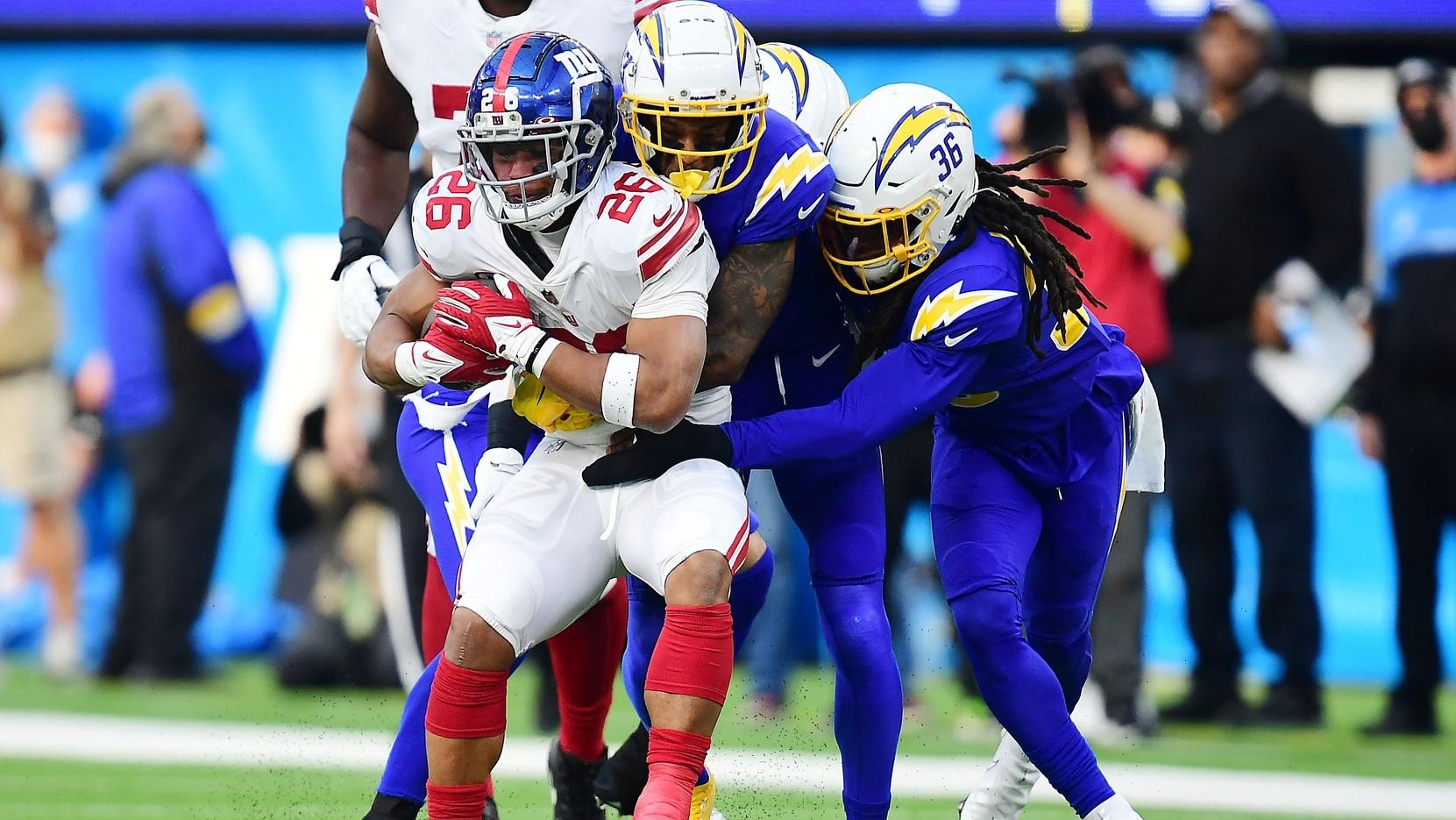 Dec 12, 2021; Inglewood, California, USA; New York Giants running back Saquon Barkley (26) is stopped by Los Angeles Chargers defensive back Trey Marshall (36) and the defense during the first half at SoFi Stadium.